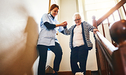 woman helps an elderly woman downstairs