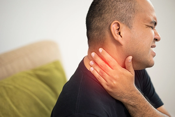 A man grips his neck wincing in pain