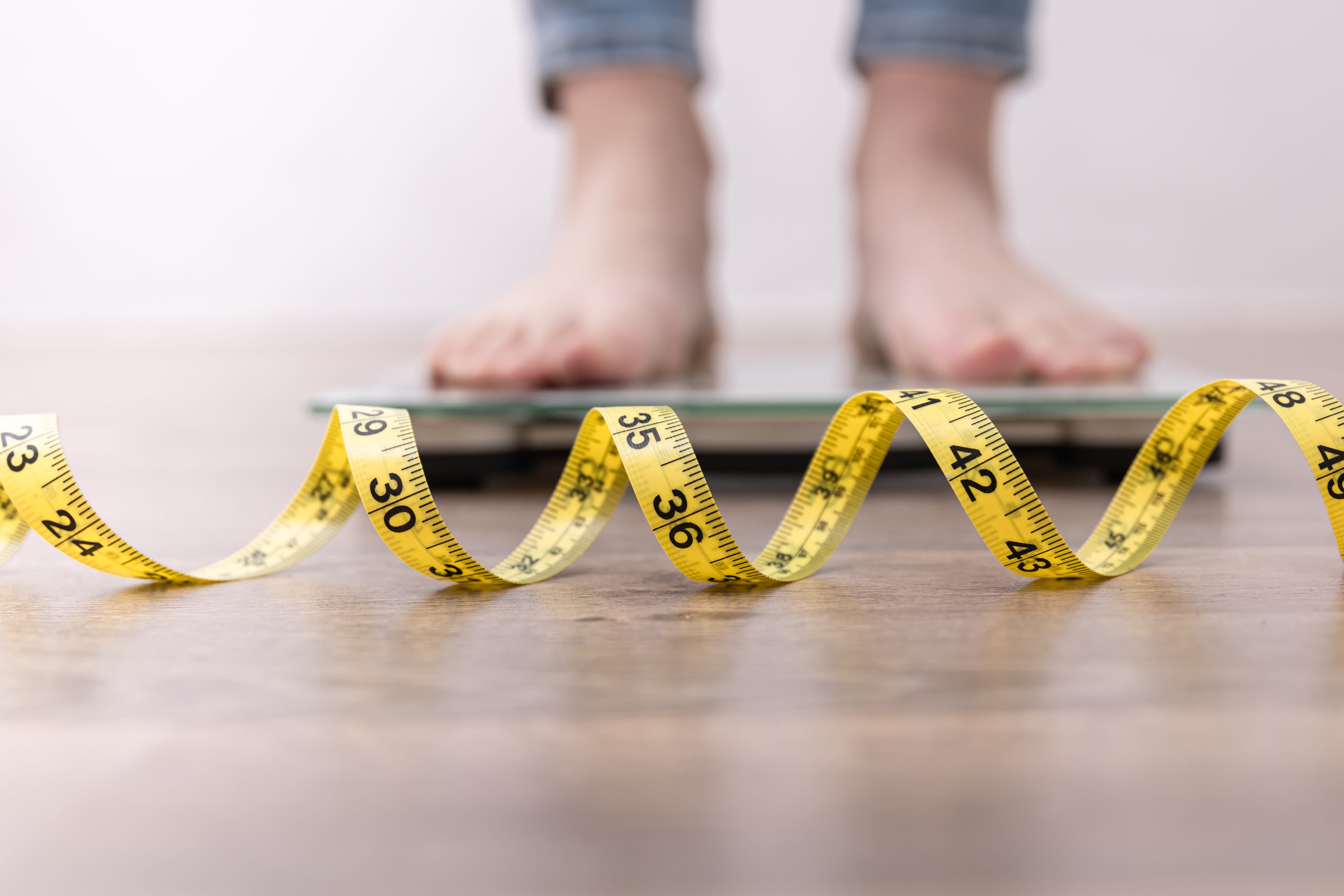 person standing on scale with tape measure